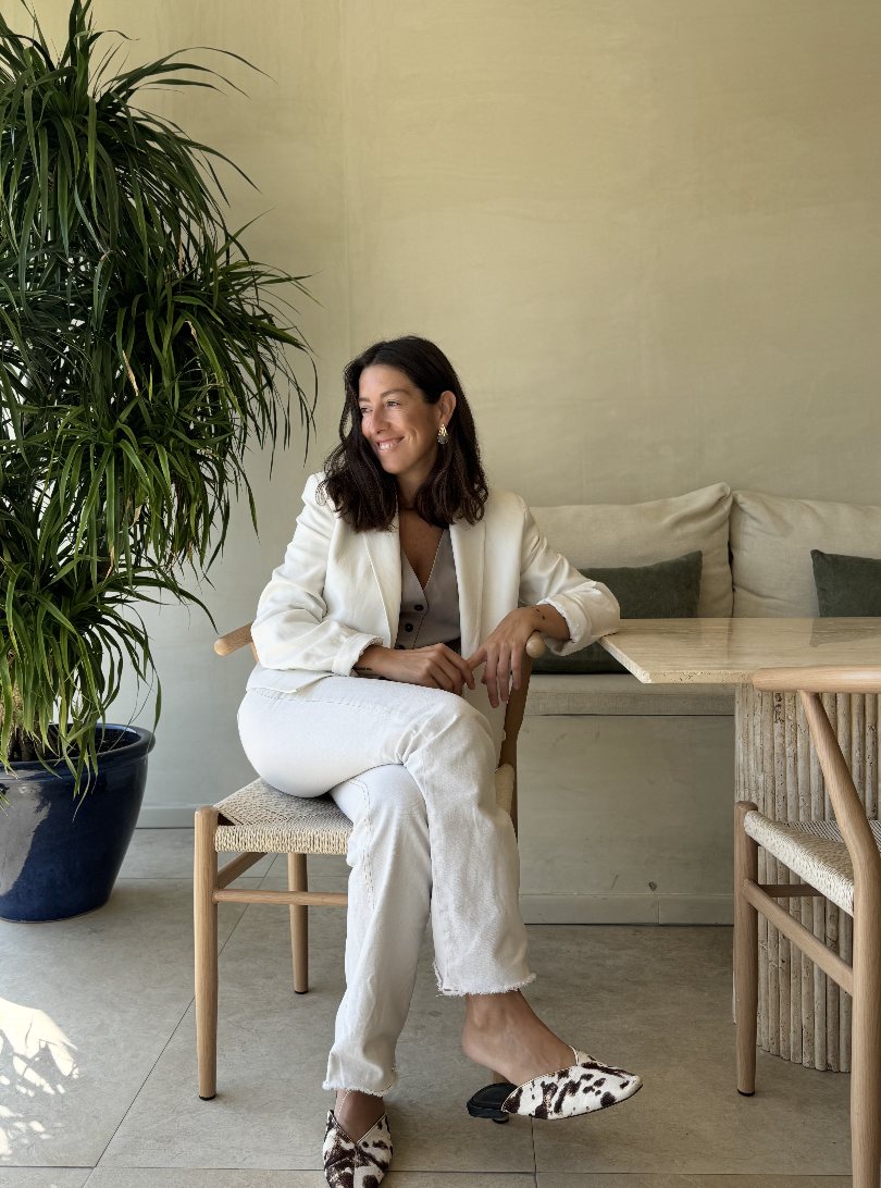 Maria Soledad Montemurro, founder of Atelier M, seated beside a travertine table